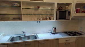 A kitchen with a stainless steel sink, a kettle, a microwave, and wooden cabinets. - Apartment - Sleeps 5 - Parking - Balcony (Thessaloniki)