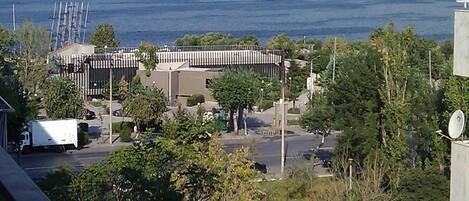 A coastal view with a modern building featuring a curved roof and a parking area.