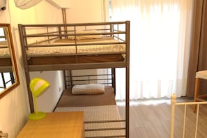 Une chambre avec un lit superposé, un bureau et une lampe.