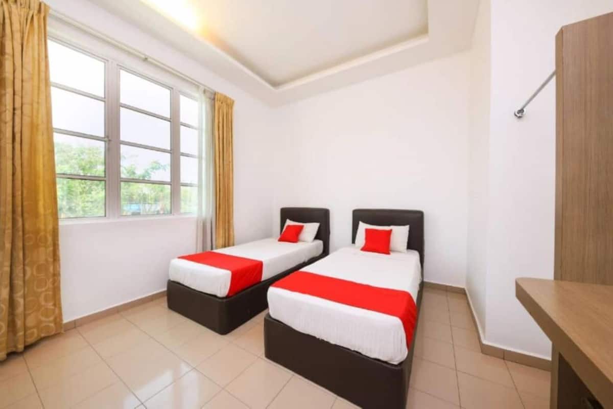 A hotel room with two beds, a window with curtains, and a wooden bench.