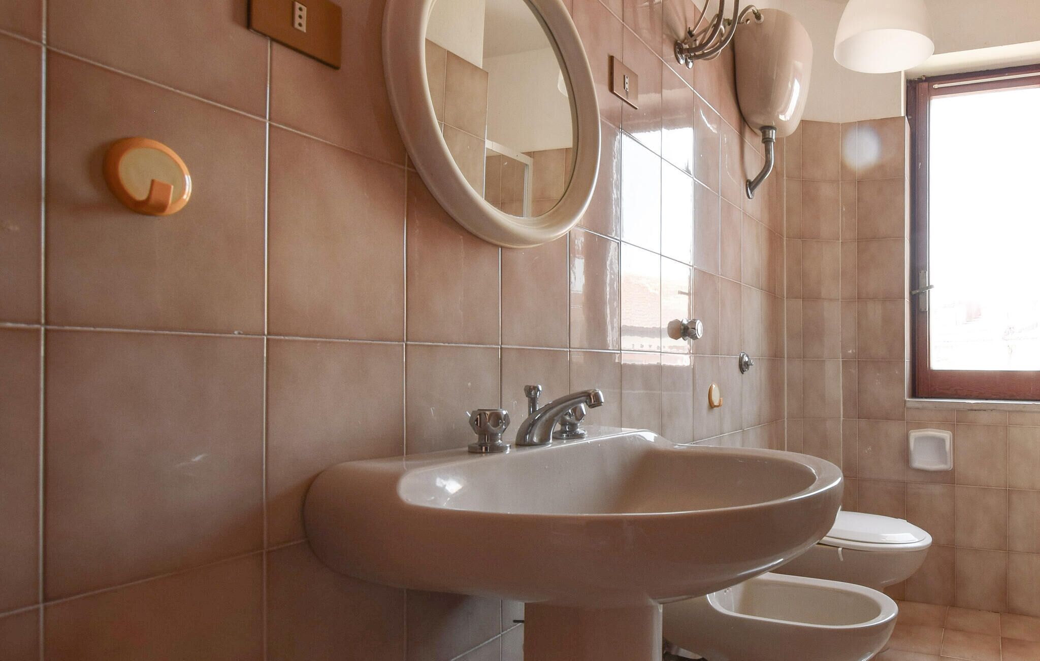 A bathroom with a large sink, a mirror, and a toilet.