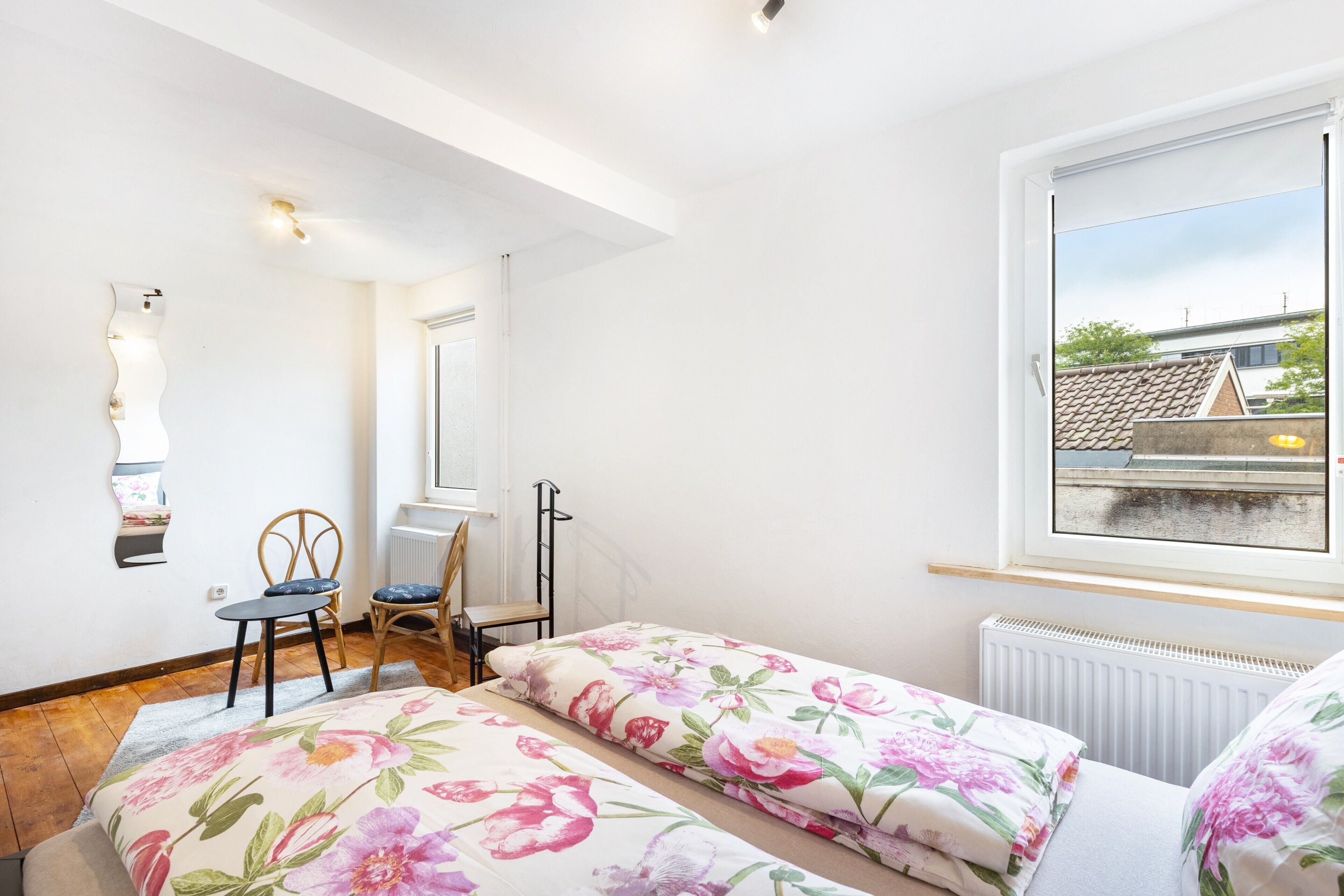 Une chambre avec deux lits, une fenêtre, un radiateur et une chaise.