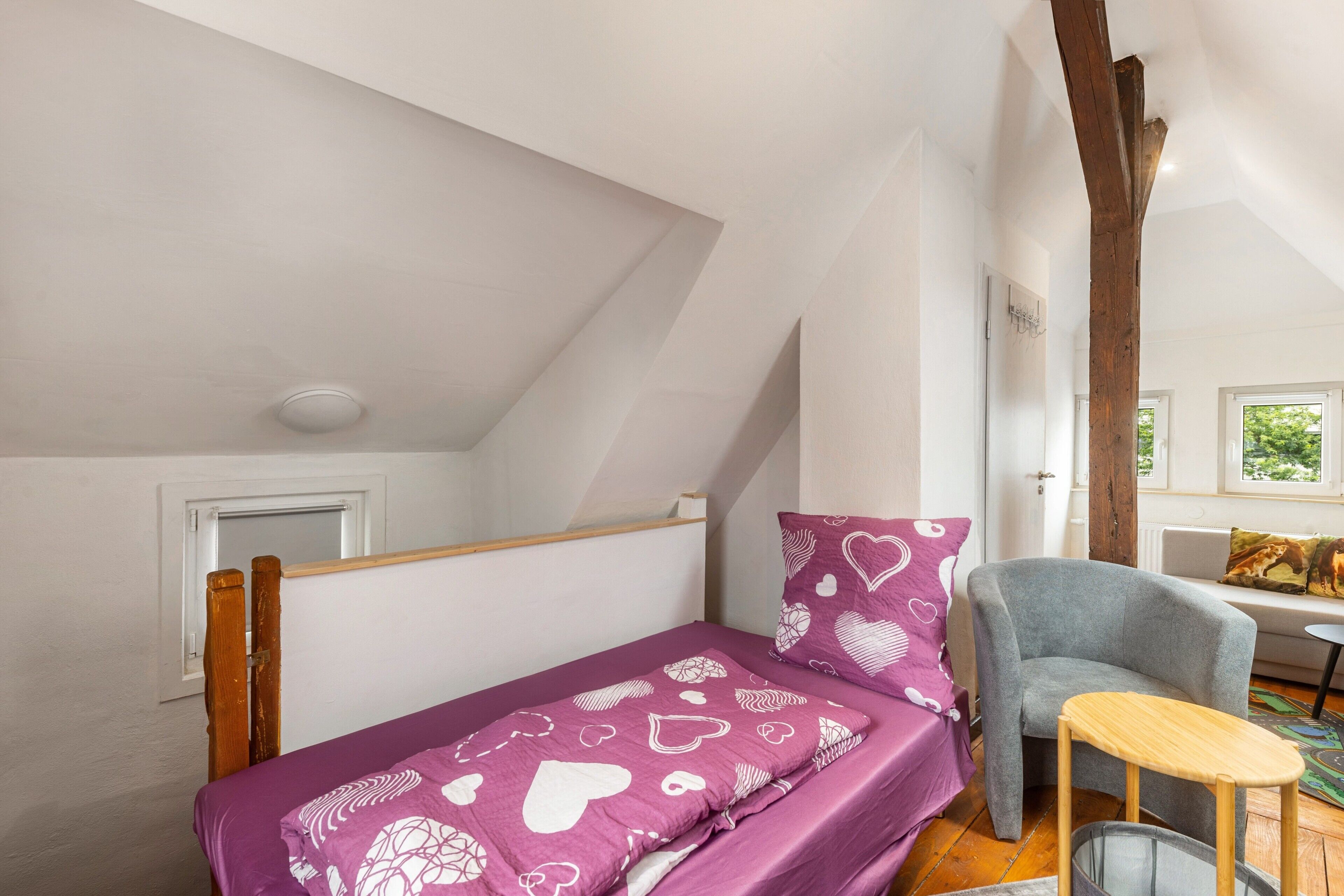 Une petite pièce agréable et confortable, avec un lit, une chaise, une table et une fenêtre.