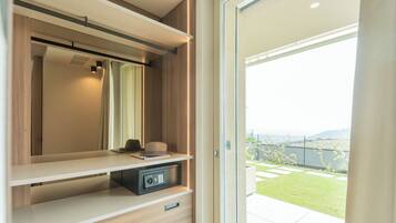Ein modernes Zimmer mit einer Schiebeglasdoor zum Balkon, einem fest eingebauten Safe und einem minimalistischen Design.