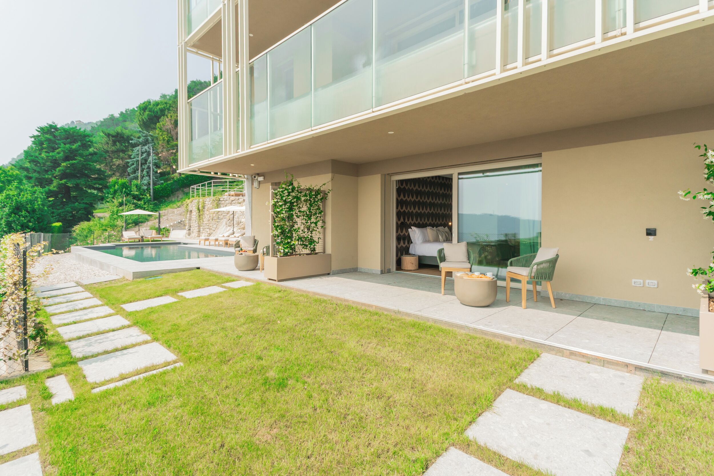 Ein modernes Haus mit Glasbalkon, Schwimmbad und gepflegtem Rasen.