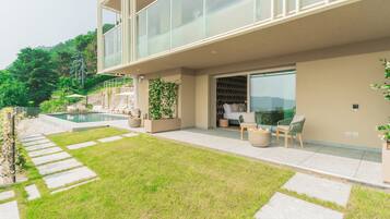 Ein modernes Haus mit Glasbalkon, Schwimmbad und gepflegtem Rasen.