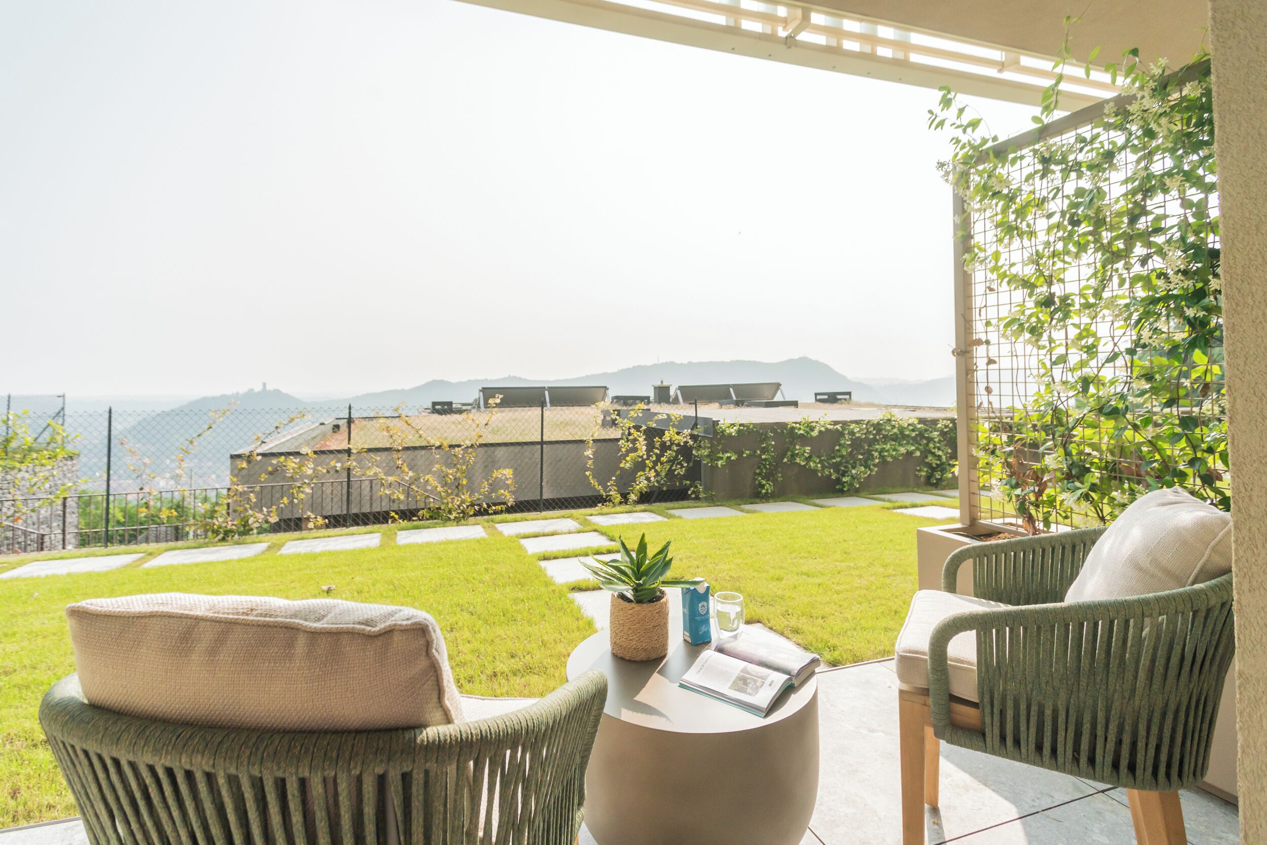 Une terrasse avec des chaises en osier, une petite table et un pot de fleurs.