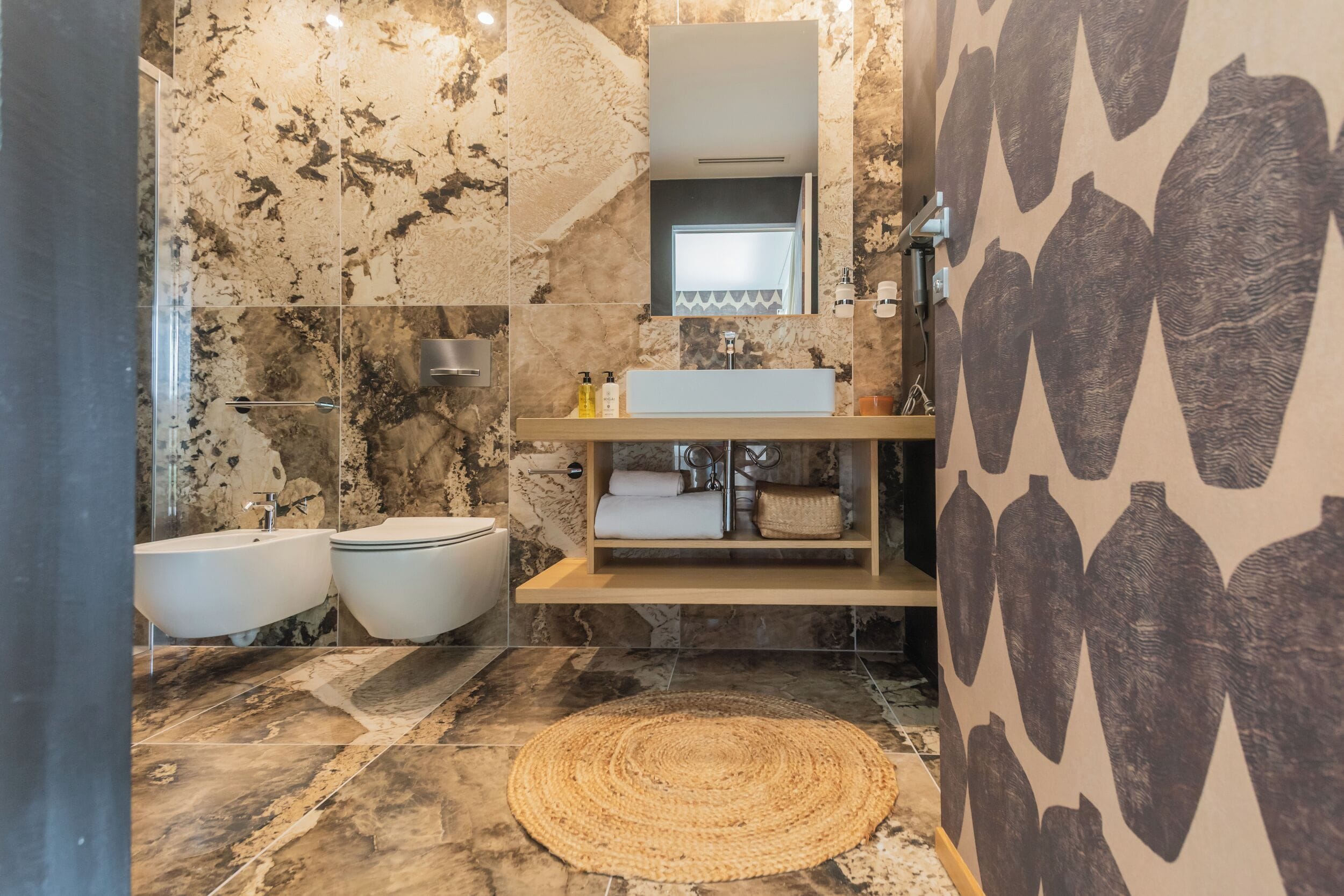 A modern bathroom with a marble floor, two sinks, a large mirror, and a wall-mounted shelf with toiletries.