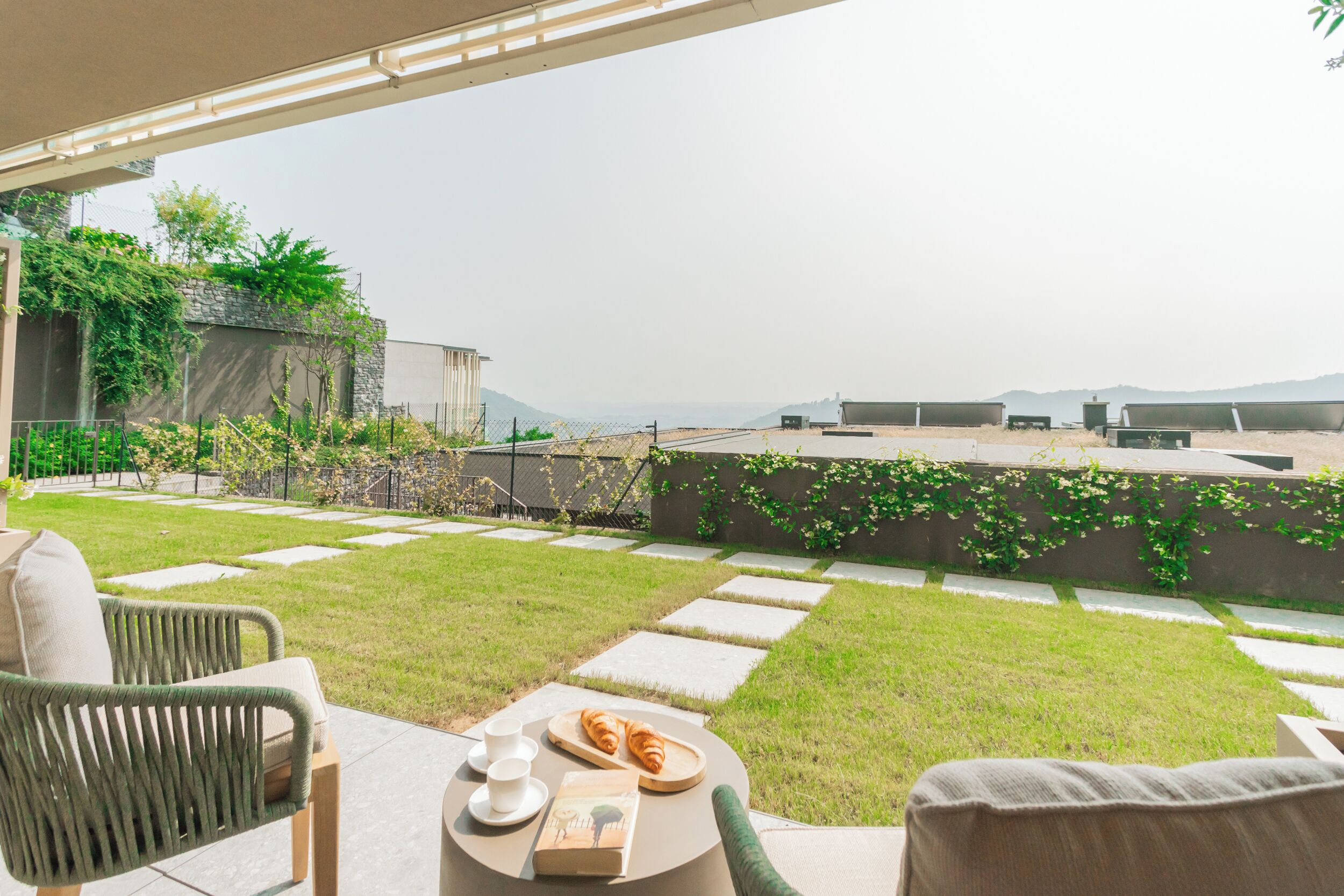 Eine Terrasse mit Esstisch, bereitgedeckt für ein Frühstück, Sitzgelegenheiten im Freien und Blick auf die umliegende Landschaft.
