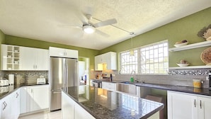 Una cocina moderna con armarios blancos, un refrigerador de acero inoxidable y una isla grande con encimera negra.