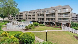 A multi-story residential building with balconies, a central courtyard, and surrounding greenery. - Shipwatch Pointe II-K103 1BR Condo in Shore Dr (Myrtle Beach)