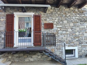 A stone building with a wooden balcony, a potted plant, and a sign. - Keila Holiday Home – Mountains, Peace & WiFi (Colorina)