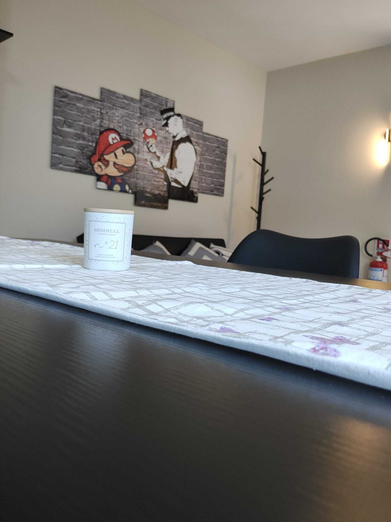 Un'area pranzo con un tavolo apparecchiato per due, una parete con un quadro di Mario e Luigi, e un contenitore con l'etichetta "Mindfull".