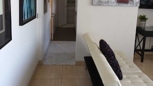A modern living room with a white sofa, a painting, and a TV on the wall. - Lovely condo with AC in vibrant Tijuana Excellent location main avenue SAFE (Tijuana)