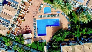 An aerial view of a resort with a central swimming pool, multiple lounge areas, and a variety of accommodations. - Morgado Group - Quinta do Morgado - Morgado Privilege (Tavira)
