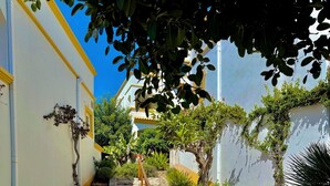 A cobblestone pathway leading up a set of stone steps to a building with a yellow and white facade. - Morgado Group - Quinta do Morgado - Morgado Privilege (Tavira)