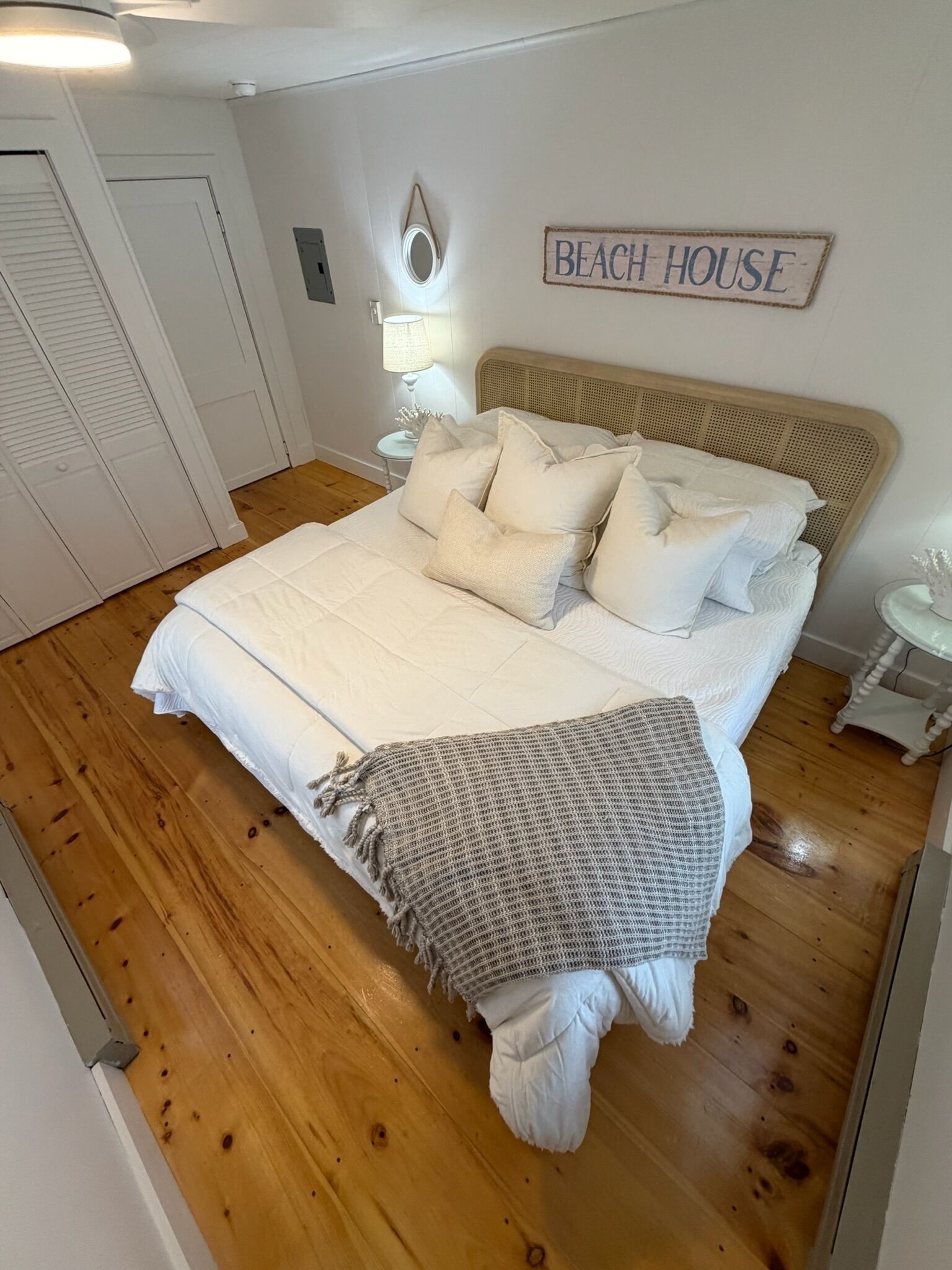 Ett sovrum med en stor säng, en sänggavel, en sänglampa och en skylt med texten ”STRANDHUS”.