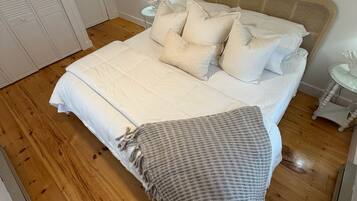Un dormitorio con una cama grande, cabecera, lámpara de noche y un letrero que dice "BEACH HOUSE".