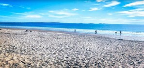 Una playa con cielo despejado y mar tranquilo.