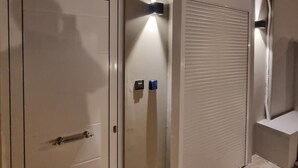 A room with a closed door, a radiator, and a wall-mounted light fixture. - Small House Lefkada Studio with Mountain View, Wi-Fi & Air Conditioning (Lefkada Town)