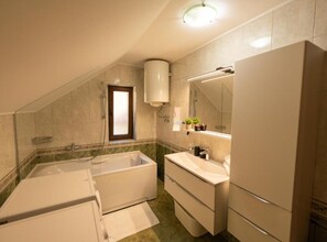 A bathroom with a bathtub, a sink, and a mirror. - Villa Narnia (Otocac)