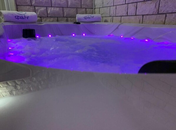 A spa bath with purple lighting and two towels labeled "spa.hr".
