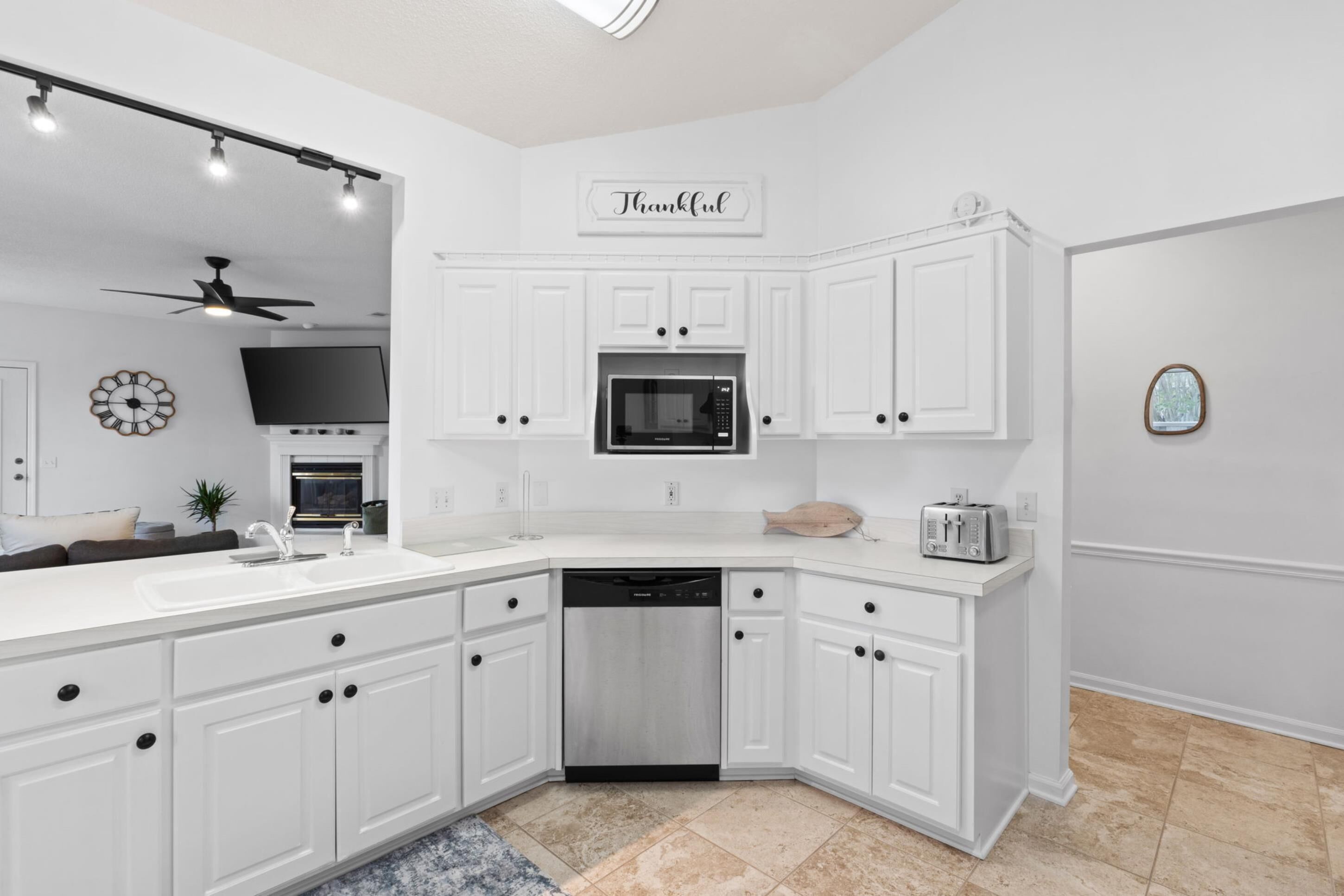 A modern kitchen with white cabinetry, a built-in microwave, a dishwasher, and a toaster.