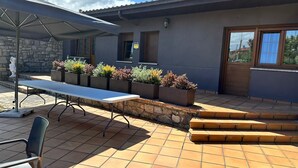 An outdoor patio with a table and chairs, stone steps, and planters with various plants. - Hotel Playa la Ñora by gaiarooms (Quintueles)