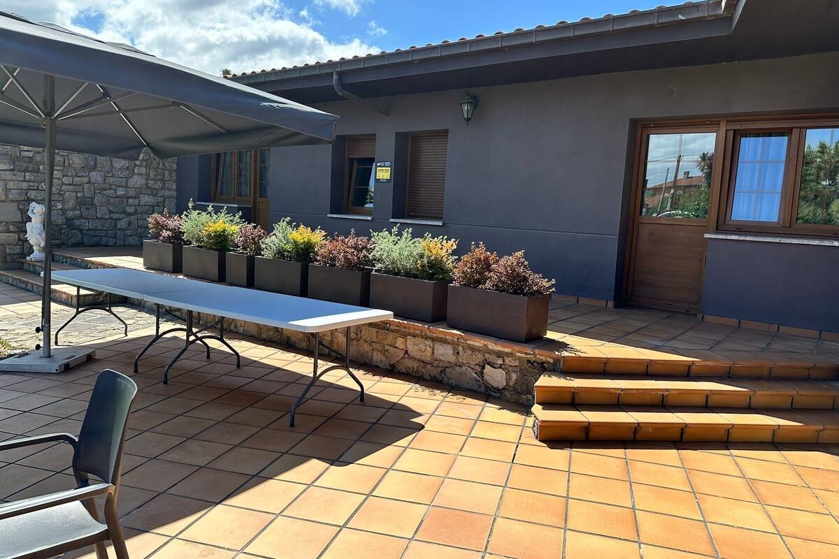 Une terrasse extérieure avec une table et des chaises, des marches en pierre et des jardinières contenant différentes plantes.