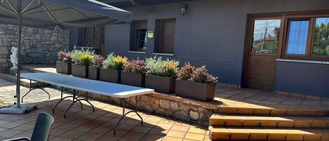 An outdoor patio with a table and chairs, stone steps, and planters with various plants.
