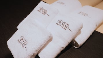 Three neatly folded white towels with embroidered text and logos, placed on a dark surface.