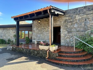 A stone building with a covered porch, a bench, and a staircase leading to the entrance. - Hotel Playa la Ñora by gaiarooms (Quintueles)