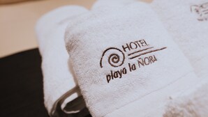 A set of white towels with embroidered text indicating a hotel and location. - Hotel Playa la Ñora by gaiarooms (Quintueles)