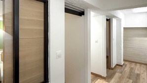Un pasillo con una mesa de madera, paredes blancas y una puerta corredera.