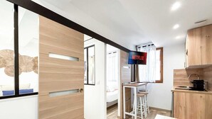 Eine moderne Küche mit Holzausstattung, einem integrierten Fernseher, der 'NETFLIX' anzeigt, und einer Essecke mit Hockstühlen.