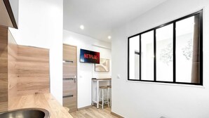 Een moderne keuken met een houten aanrecht, een spoelbak en een barkruk. Een televisiescherm toont het Netflix logo.