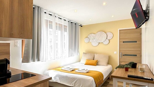 A modern hotel room with a bed, a desk, a TV, and a small kitchenette. - Hoche A 12 - Studio Apartment, Sleeps 2 (Paris)