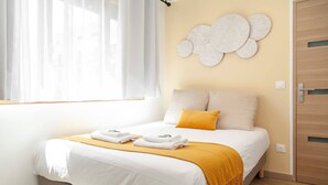 A bedroom with a bed, a window with sheer curtains, a wall-mounted decorative piece, and a wooden door. - Hoche A 12 - Studio Apartment, Sleeps 2 (Paris)