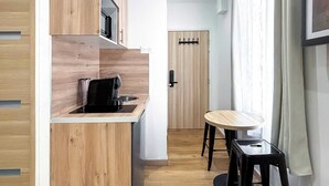 Cozinha compacta com armários de madeira, pia e um pequeno espaço de refeições com mesa e banquetas.