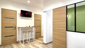 Une chambre à coucher moderne avec un lit, un bureau et un tabouret, ainsi qu’un téléviseur fixé au mur.