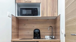 Een praktische kitchenette met een magnetron, koffiezetapparaat en een kleine koelkast.