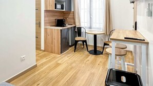Ein kleines Zimmer mit Küchenzeile, Essbereich und einem Bett.
