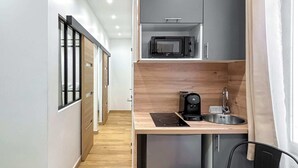 Eine kleine Küche mit integriertem Mikrowellenherd, Kaffeemaschine und Kühlschrank.