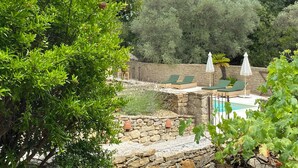 Un muro de piedra con una piscina y sillones de descanso.