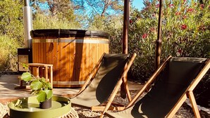 Un área de estar al aire libre con sillones, una mesa de madera y un jacuzzi.