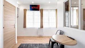 A modern room with a wooden door, a table with a remote, and a sign indicating a Netflix service.