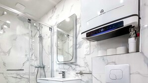 A modern bathroom with a glass-enclosed shower, a white vanity with a mirror, and a toilet.