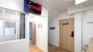 Moderni sisustus, jossa on näkyvissä ovi, naulakko ja seinälle kiinnitetty kyltti, jossa lukee ”NETFLIX”.