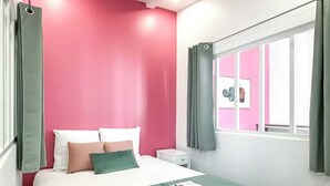 Ein ordentlich eingerichtetes Schlafzimmer mit Bett, Kissen, Nachttisch und einem Fenster mit Vorhängen.