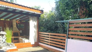A garden with a wooden pergola, a brick patio, and a variety of plants. - Comfort bungalow (Saint-Paul)